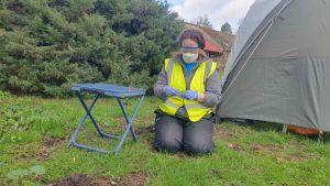 Person in high visibility jacket and PPE handling samples in a field