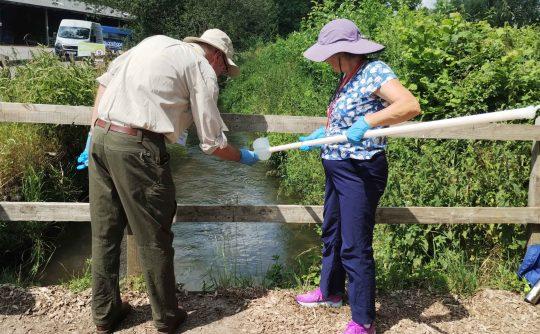 Two people collecting a water sample from a river